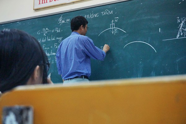 Teacher writing mathematics equations on a chalkboard